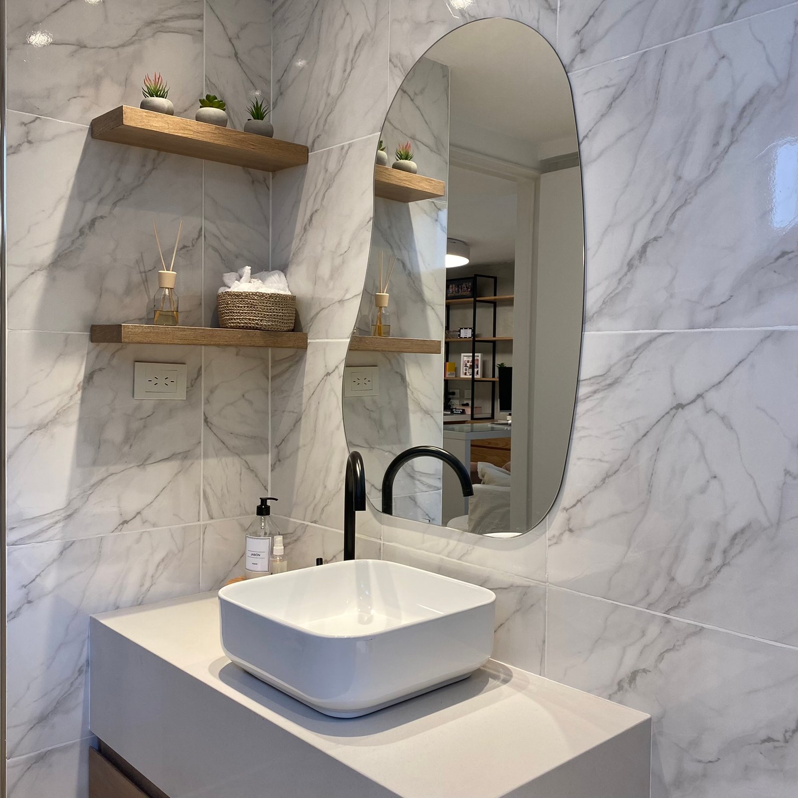 Baño moderno con lavabo sobre encimera y espejo ovalado — proyecto Estudio MDBK, por MDBK Arquitectura, en Almagro
