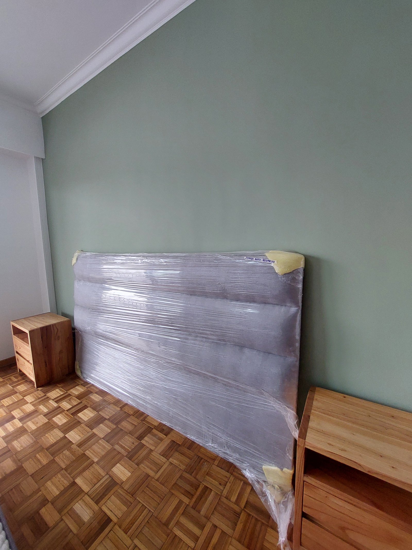 cama envuelta en plástico, paredes verdes y piso de madera — proyecto FLORES, por Arquitecta, en Flores
