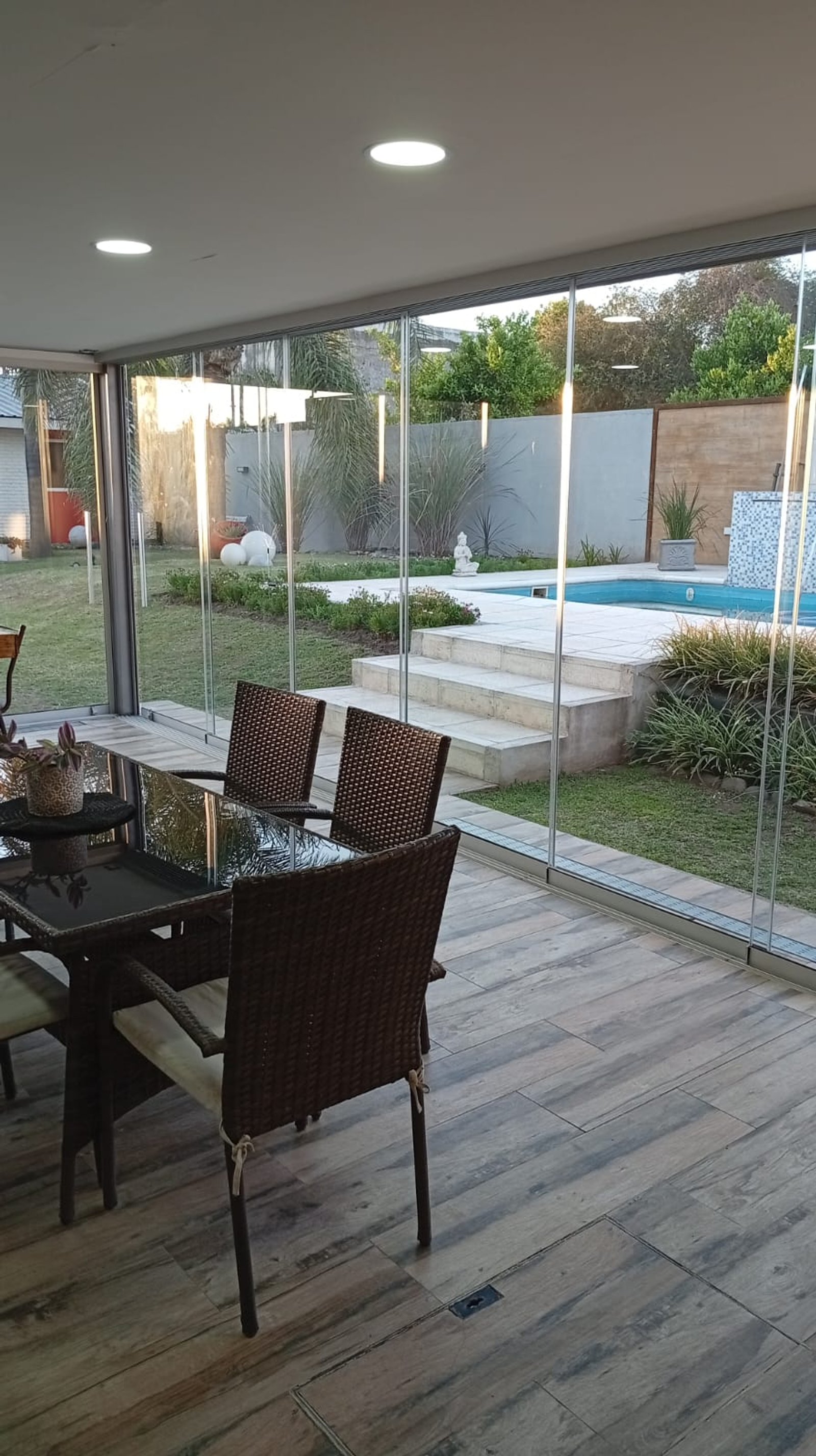 Comedor exterior moderno con mesas de vidrio y sillas de ratán — proyecto ARGUELLO, por GARCIA RECTA DESIGN, en Argüello