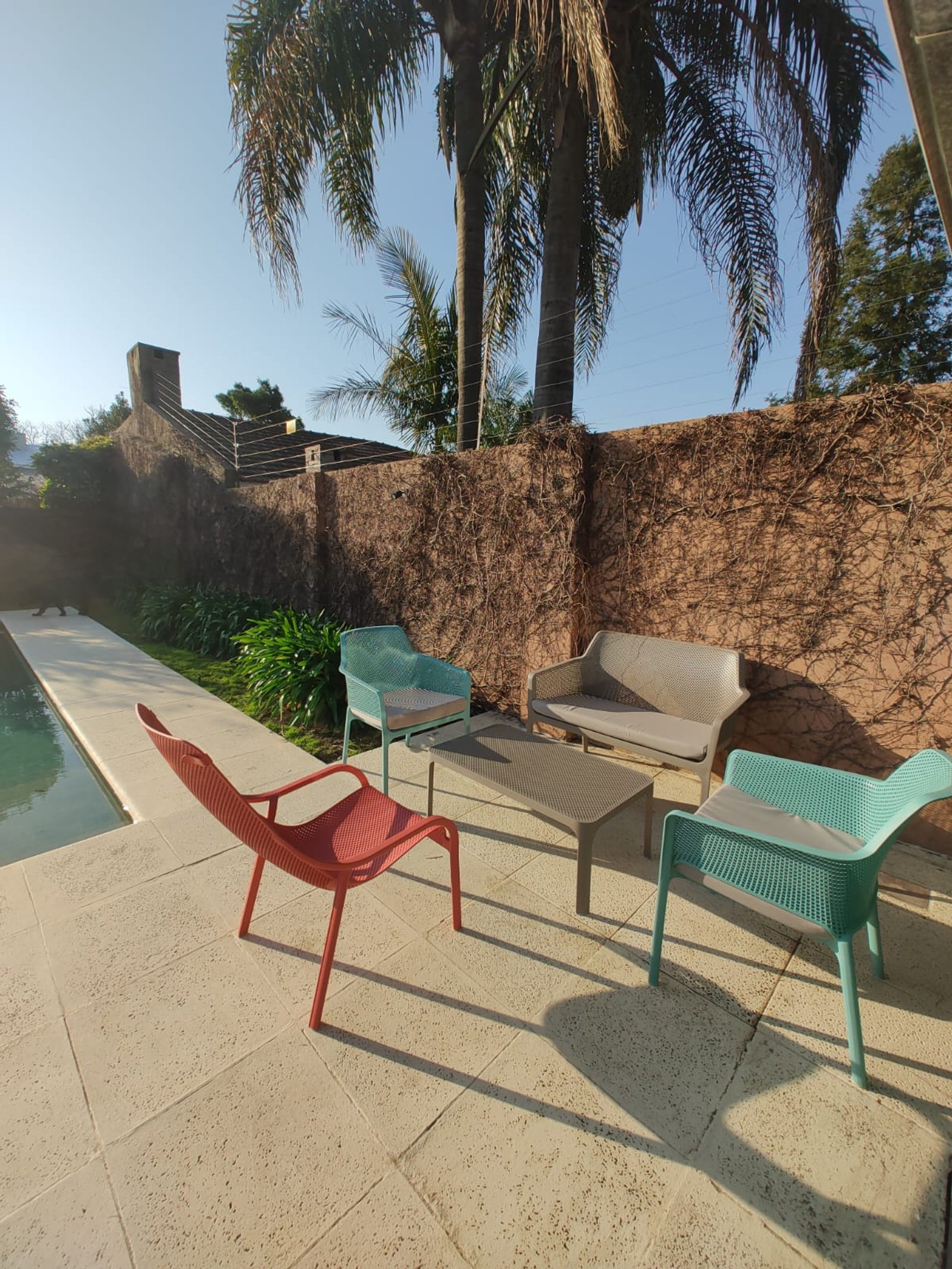 Patio moderno con piscina y sillones bajo palmeras — proyecto Juegos de Livings Amplios, por Casa Nuñez
