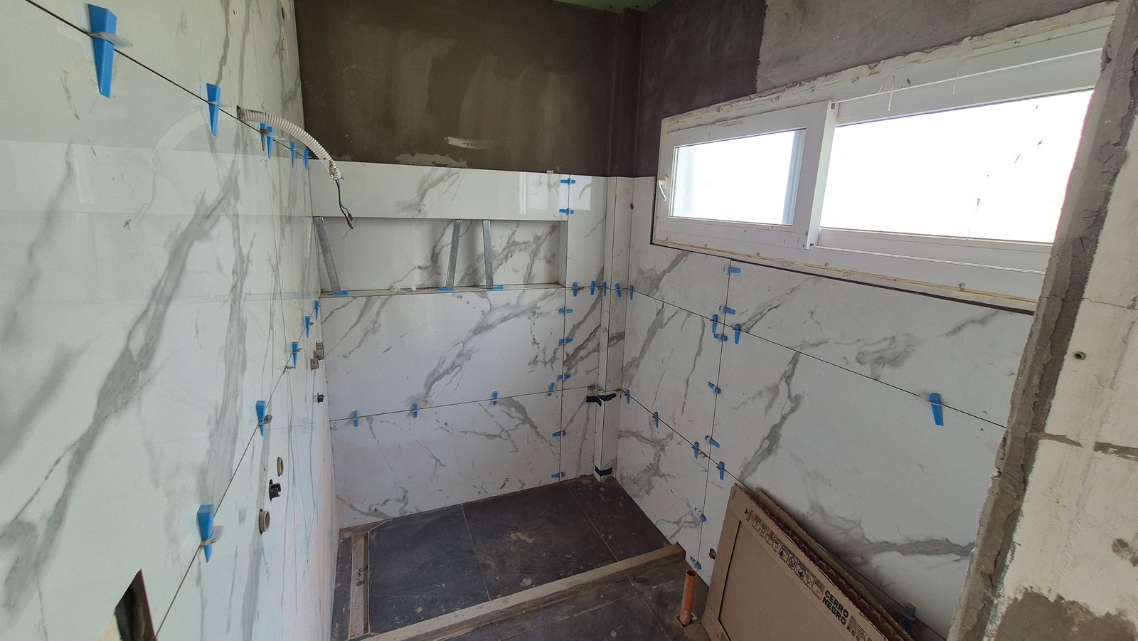 Banheiro em construção com azulejos tipo mármore e janelas — projeto Baño - Remodelación Soho, por RenovArqui, em Palermo