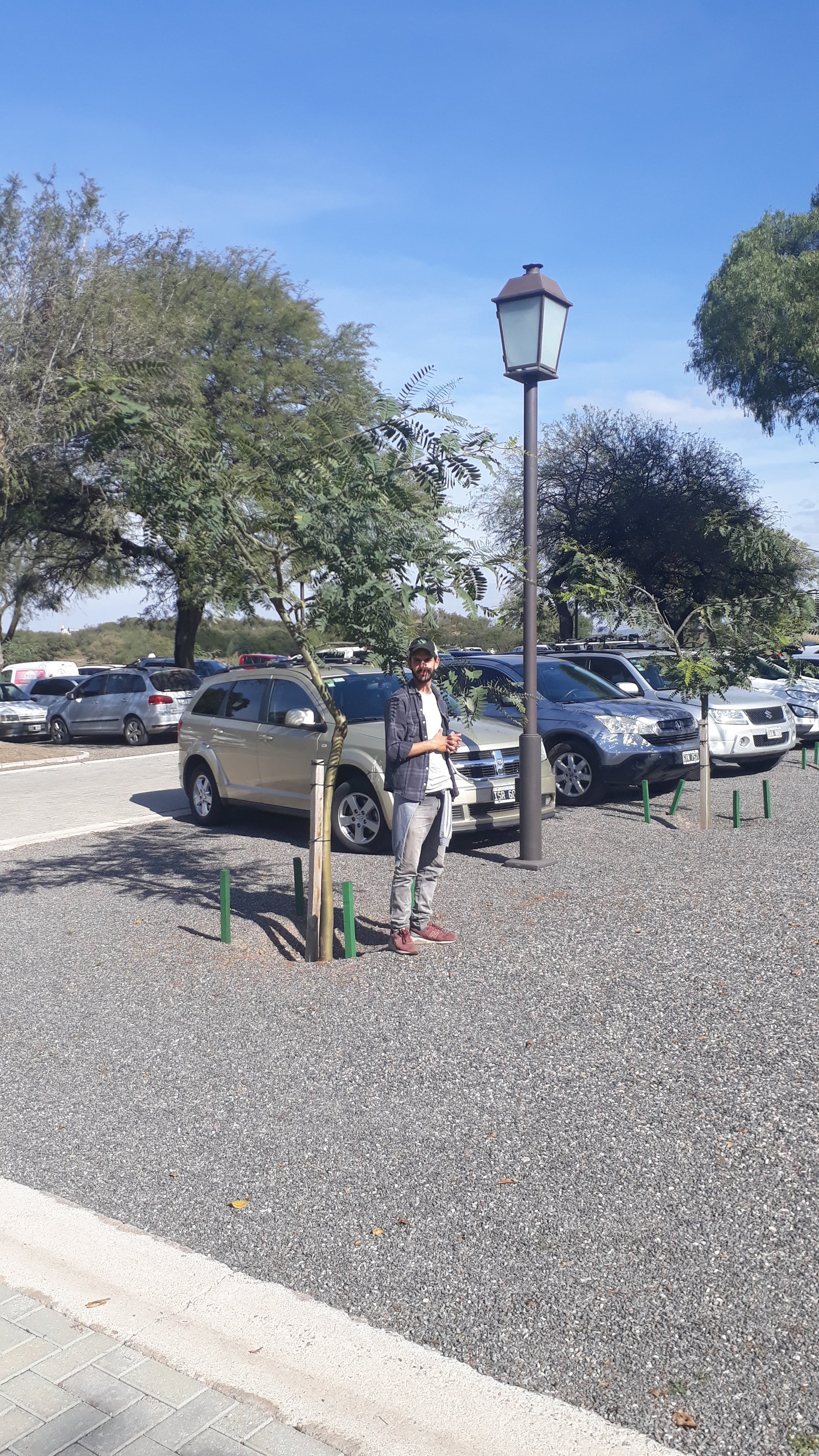 Homem em estacionamento externo com carros e poste de luz — projeto El Terrón, por Estudio Rifahi, em Mendiolaza