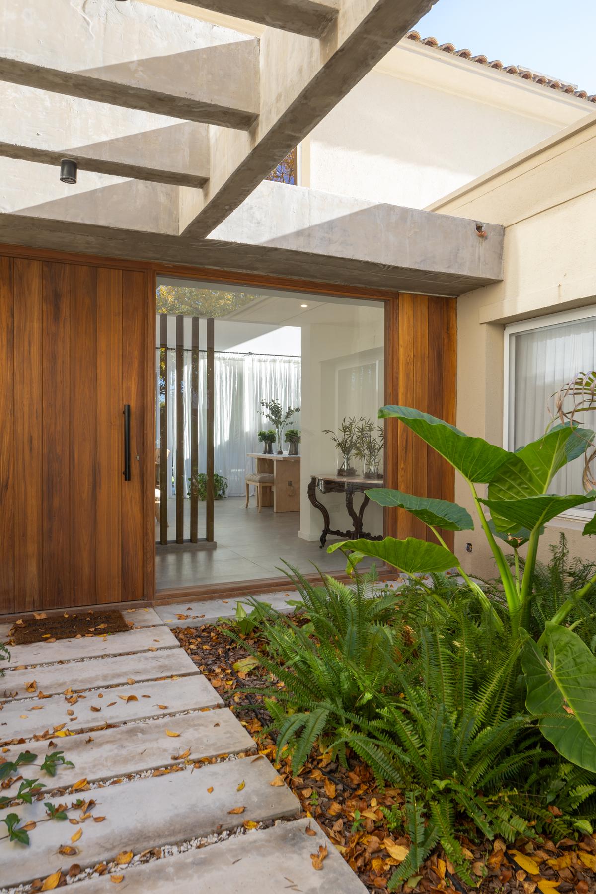 Fachada moderna de madeira e concreto com vegetação exuberante — projeto Reforma Vasco, por Pedro Busso Arq, em Tigre