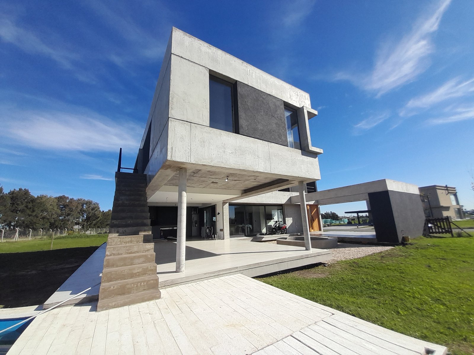 Casa moderna brutalista con deck de madera y amplias ventanas — proyecto Puerto Nizuc, por Estudio Fernandez Long & asoc., en Au Dr. Ricardo Balbín km 31.5