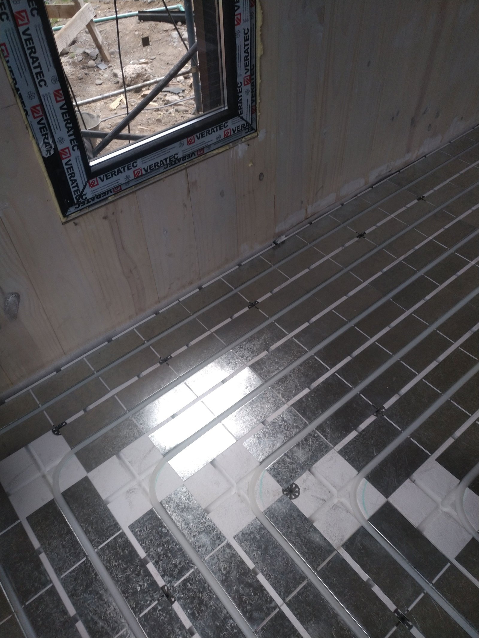 Construcción de suelo radiante con tuberías y paneles metálicos grises — proyecto Vivienda Lago Lolog, por TROKEN, en Neuquén