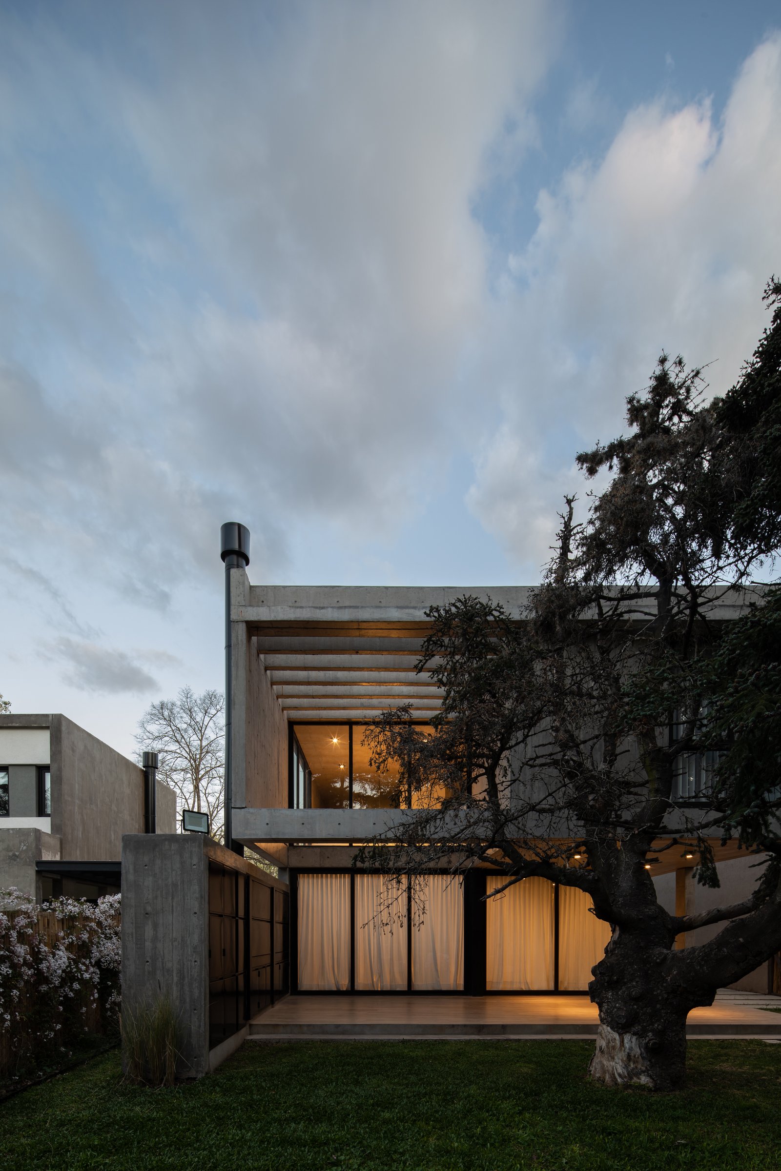 Fachada moderna brutalista con hormigón expuesto y grandes ventanales — proyecto Casa Emilia, por Grupo CRBN, en Parque Leloir