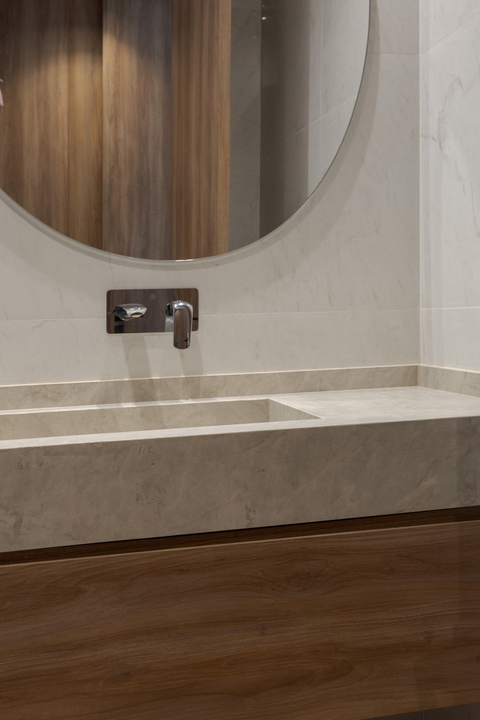Baño moderno con bacha de piedra integrada y espejo redondo — proyecto Casa PLANALTO, por Grupo CRBN, en Av. Pres. Perón 10298
