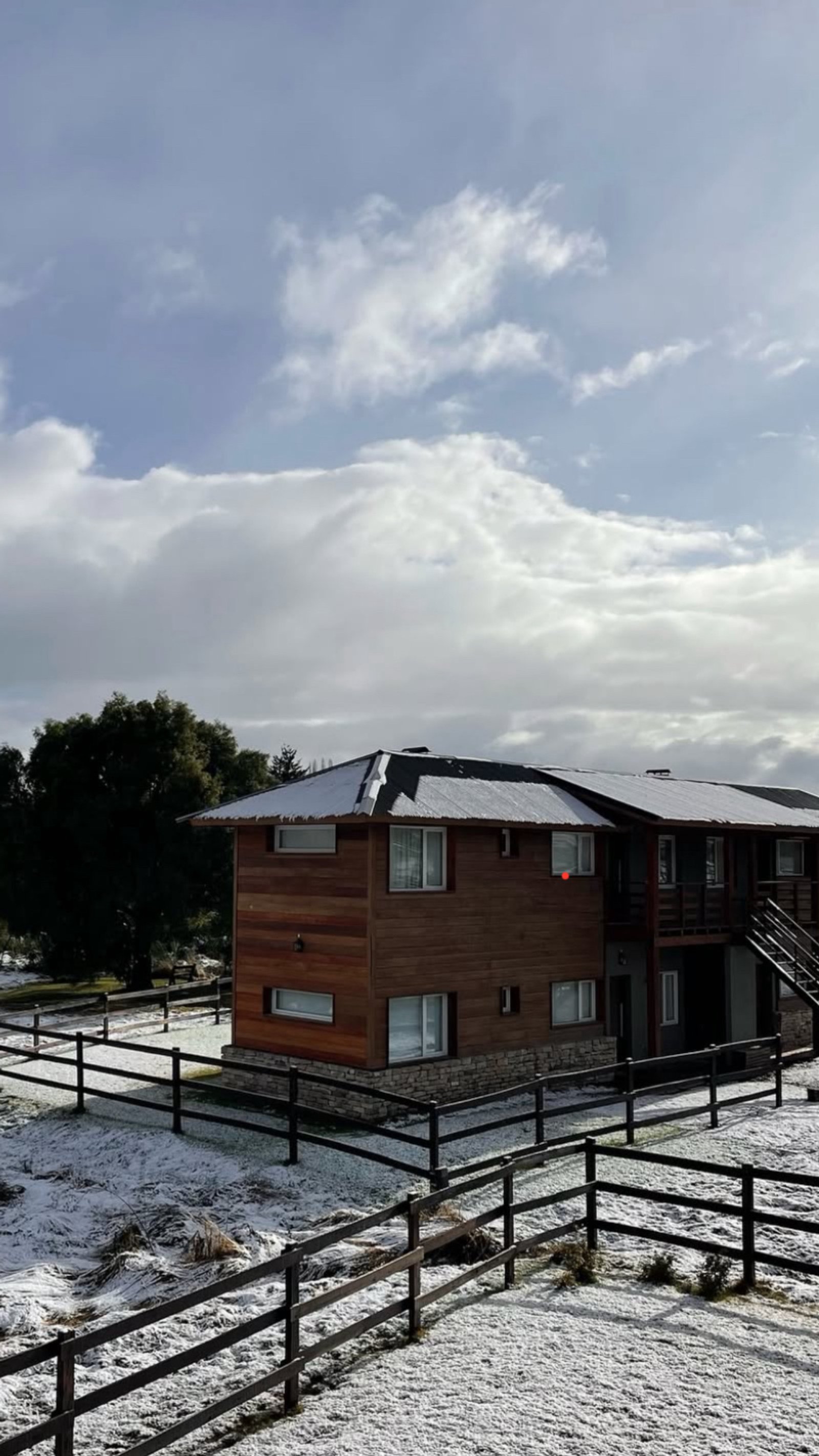 Fachada de madeira com neve e cercas escuras — projeto La Pampita, por Arquitecta Grace Overgaard, em Lago Gutiérrez