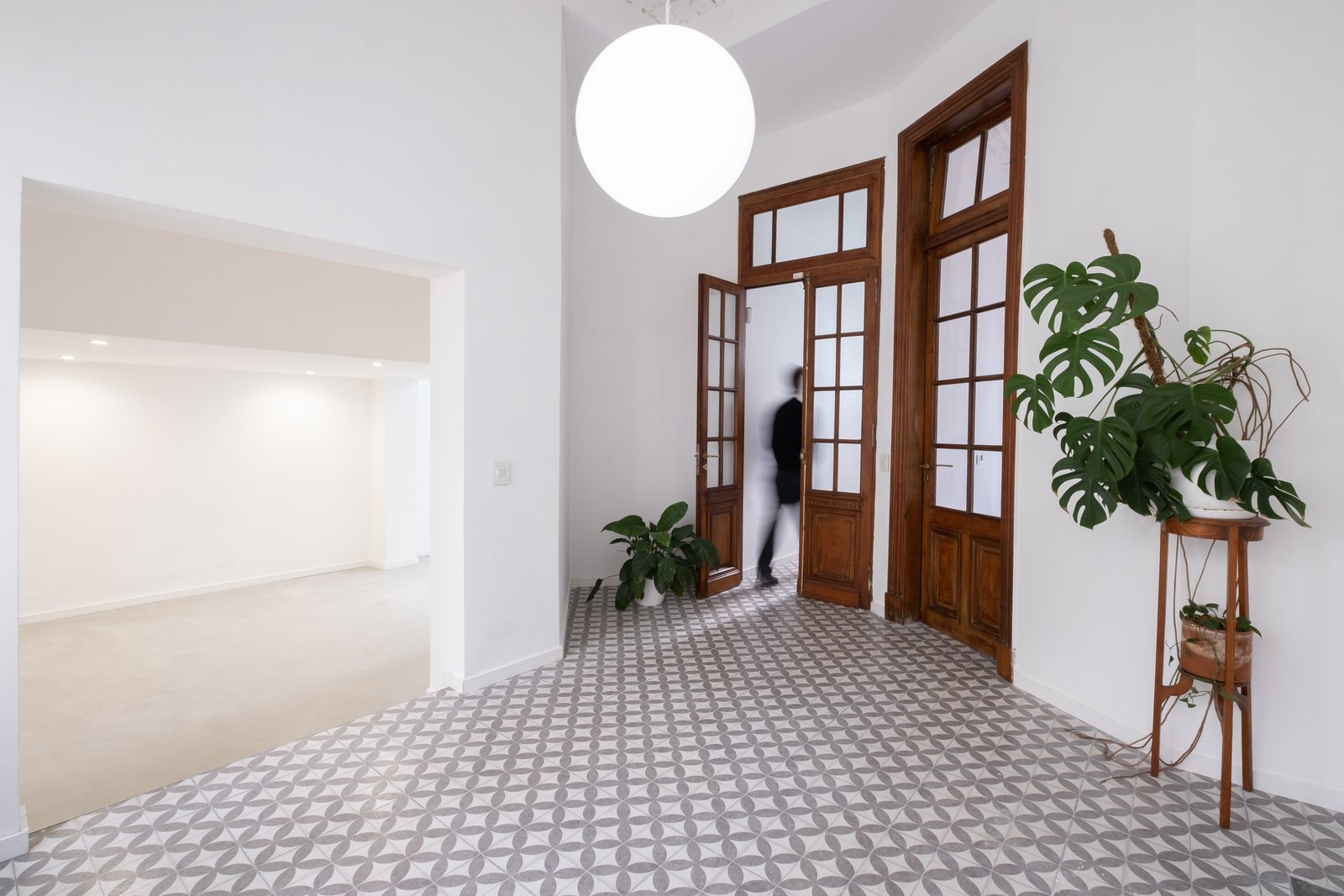 Pasillo moderno con piso geométrico y luz colgante — proyecto Casa Patio, por Herrera Ungaro, en San Cristóbal