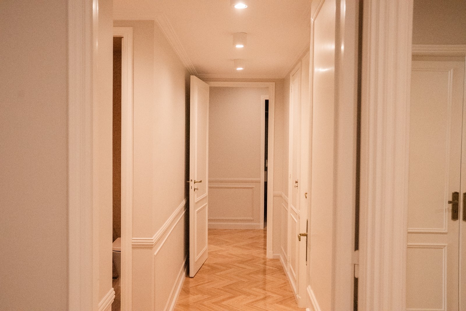 Pasillo clásico con piso de madera y puertas blancas — proyecto QUINTANA, por ESTUDIO TEZ, en Recoleta
