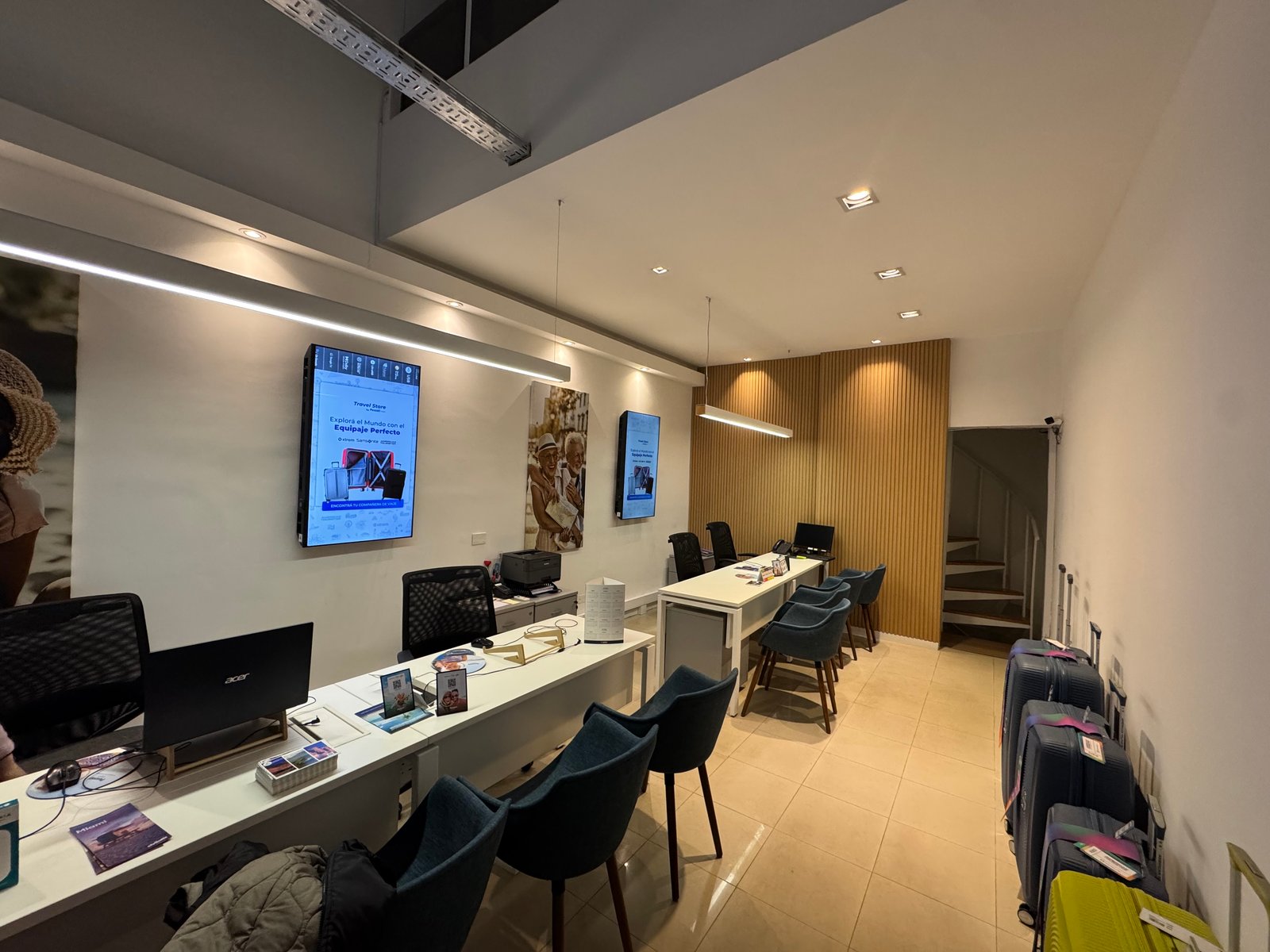 Agencia de viajes moderna con escritorio de recepción y sillas azules — proyecto Pezzati viajes , por Remodela tu local , en Buenos Aires
