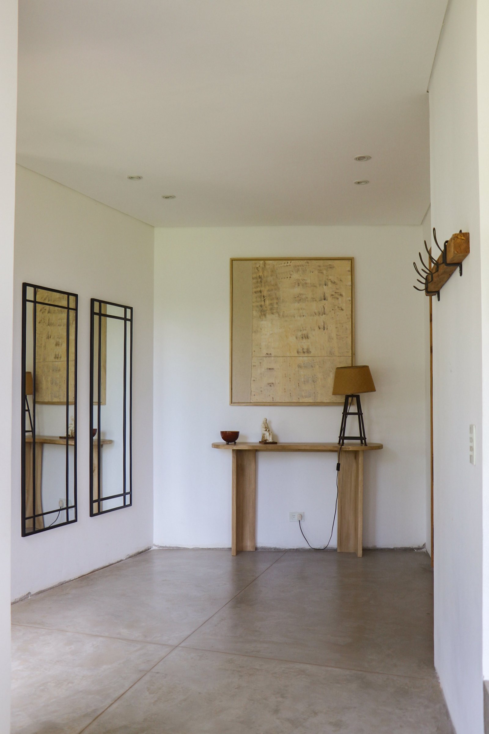 Corredor minimalista com espelhos retangulares e arte dourada — projeto Casa San Fermin 200, por R+B arquitectos, em Pasteur 662