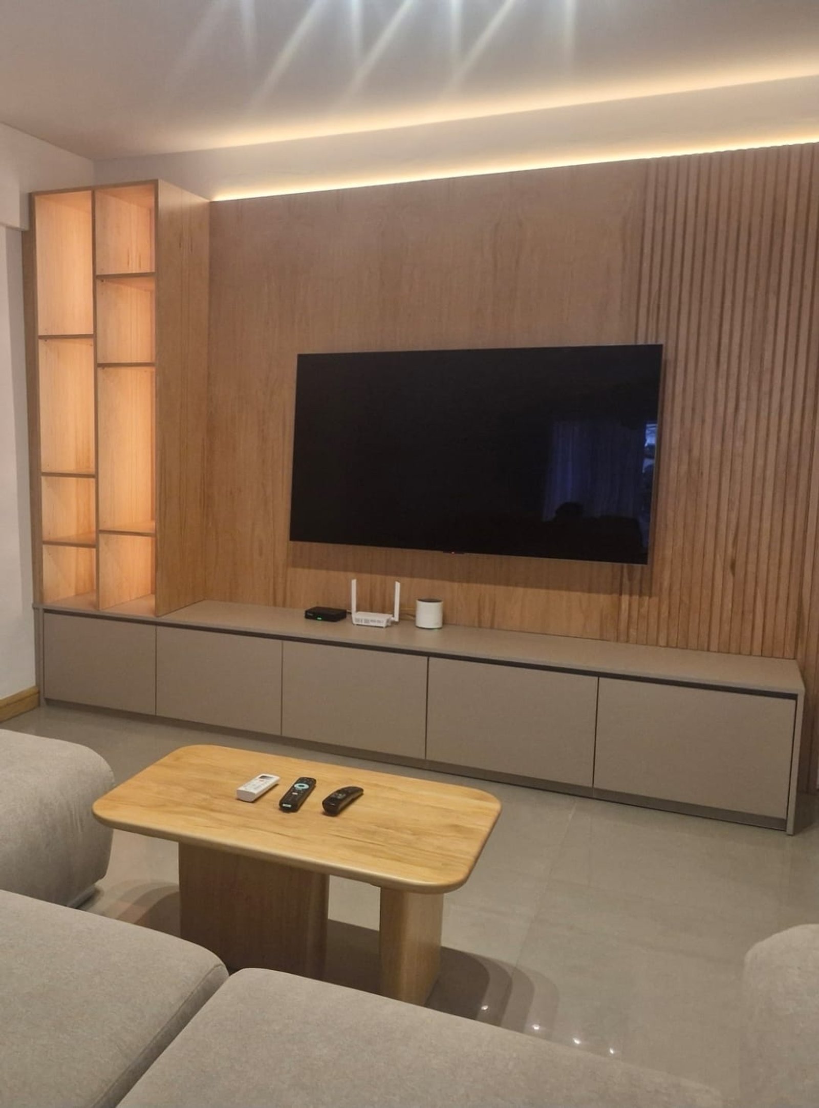 Living moderno con TV, estanterías de madera y luces indirectas — proyecto Proyecto Andonaegui - Diseño y ejecución integral living, por MJS INTERIOR DESIGNER, en Andonaegui