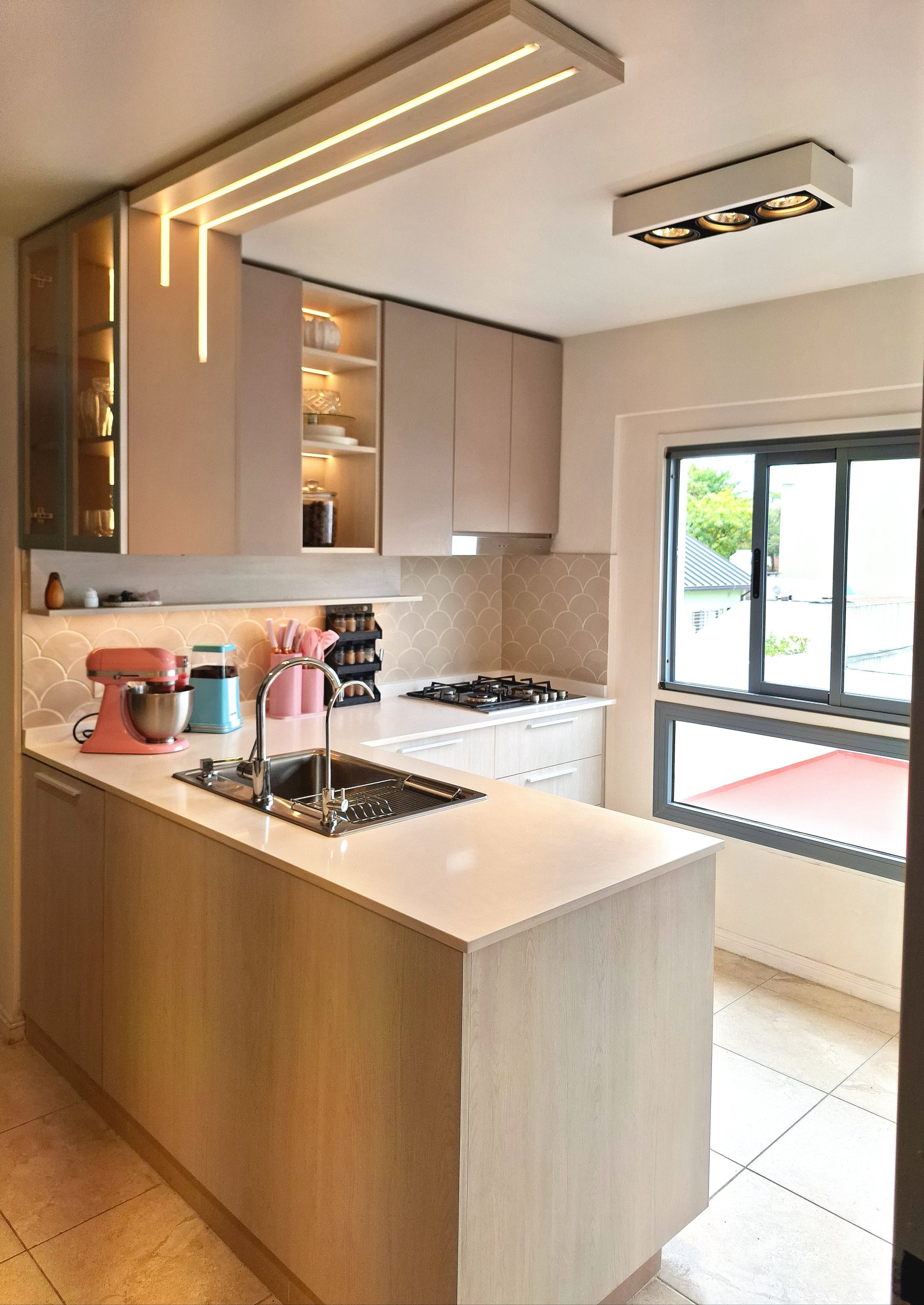 Cozinha moderna com ilha, armários de madeira e bancadas brancas — projeto PROYECTO CRAMER 3, por HALESA ESTUDIO, em Crámer