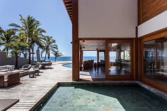 Patio con pileta, deck de madera, vistas al mar y palmeras — proyecto Residência CM, por Milcent Arquitetura