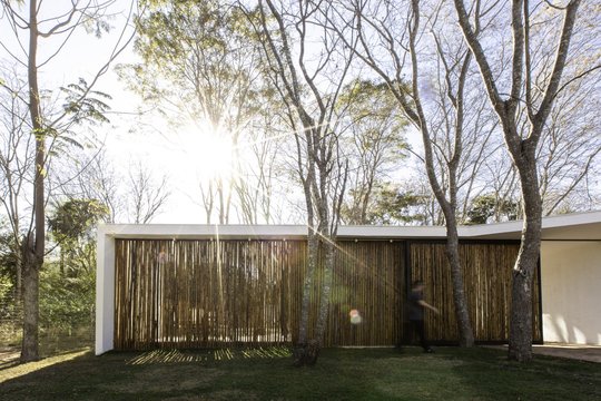 Casa contemporánea con fachada madera y grandes ventanales entre árboles — proyecto Casa Terra, por Tetro Arquitetura