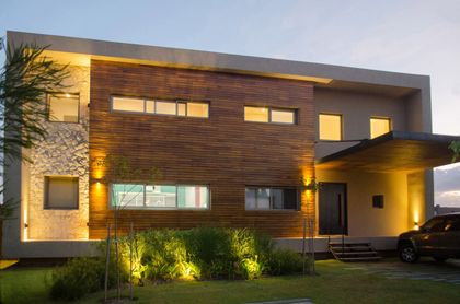 Fachada moderna de casa con revestimiento de madera y piedra — proyecto Casa Nordelta, por linearecta.arquitectura, en Nordelta
