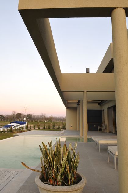 Piscina moderna con pérgola de hormigón y avión al fondo — proyecto Moderna Seducción, por Apaarquitectura, en Tigre