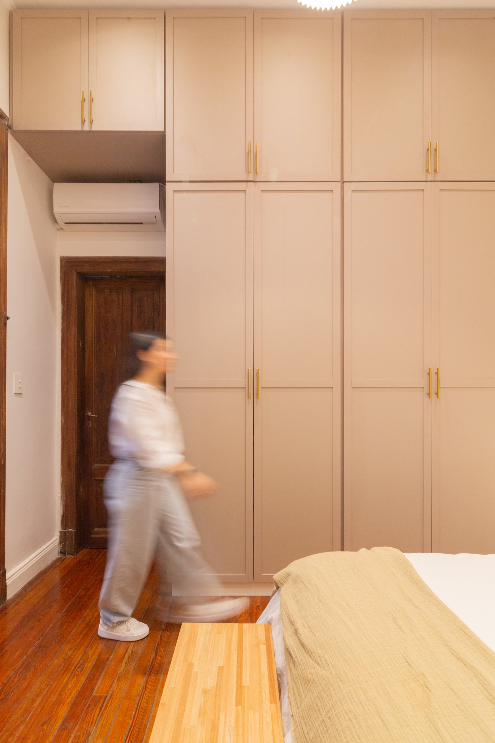 Quarto moderno com armários embutidos bege e piso de madeira — projeto Anchorena, por Martina Kleinert, em Palermo