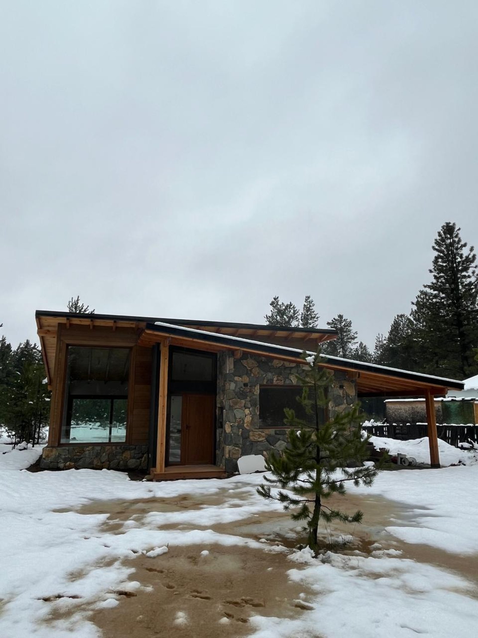 Casa moderna con techo inclinado y fachada de piedra nevada — proyecto Casa Arcoiris, por Arquitecta Grace Overgaard, en Acceso Al Challhuaco