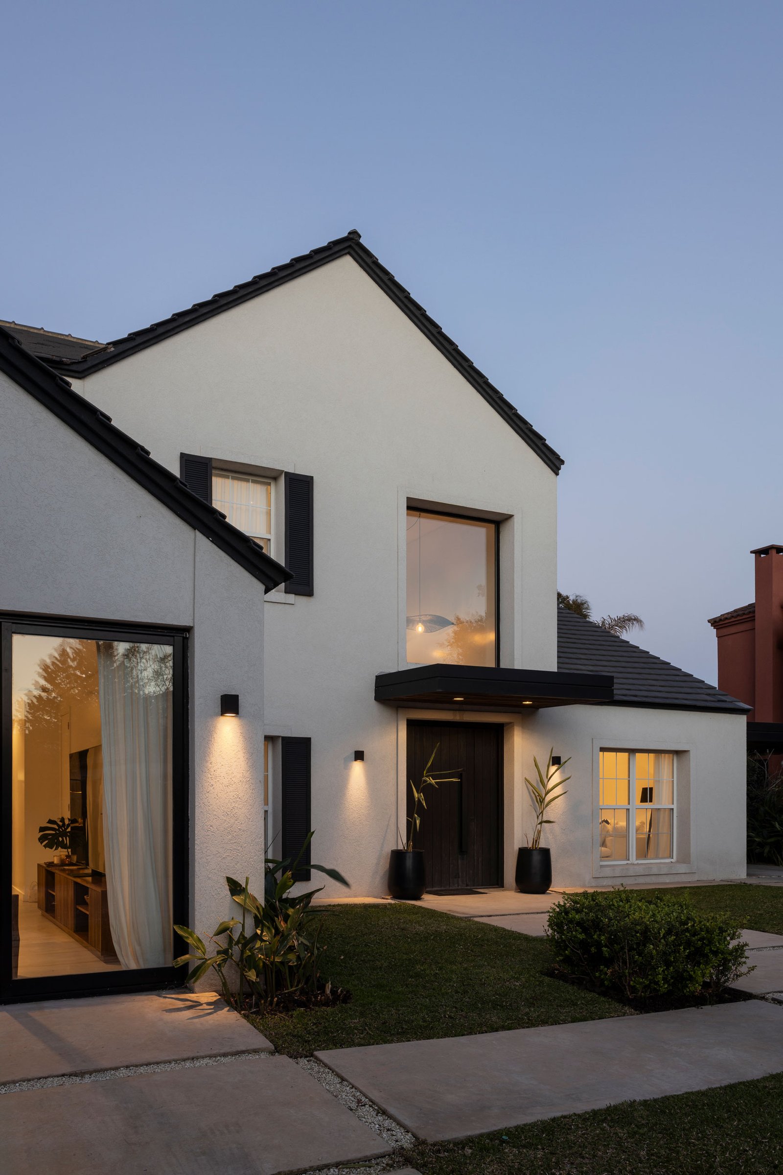 Fachada de casa moderna suburbana con iluminación cálida — proyecto REFORMA GDLT, por Rastro Estudio, en Nordelta