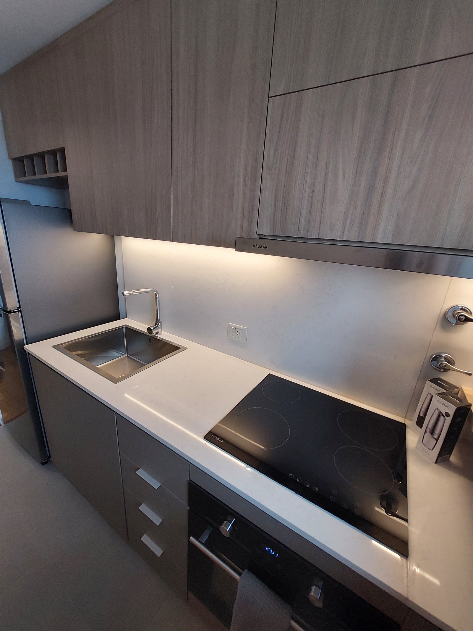Cocina moderna con gabinetes de madera natural y encimera de piedra blanca — proyecto PARAGUAY, por Arquitecta, en Buenos Aires