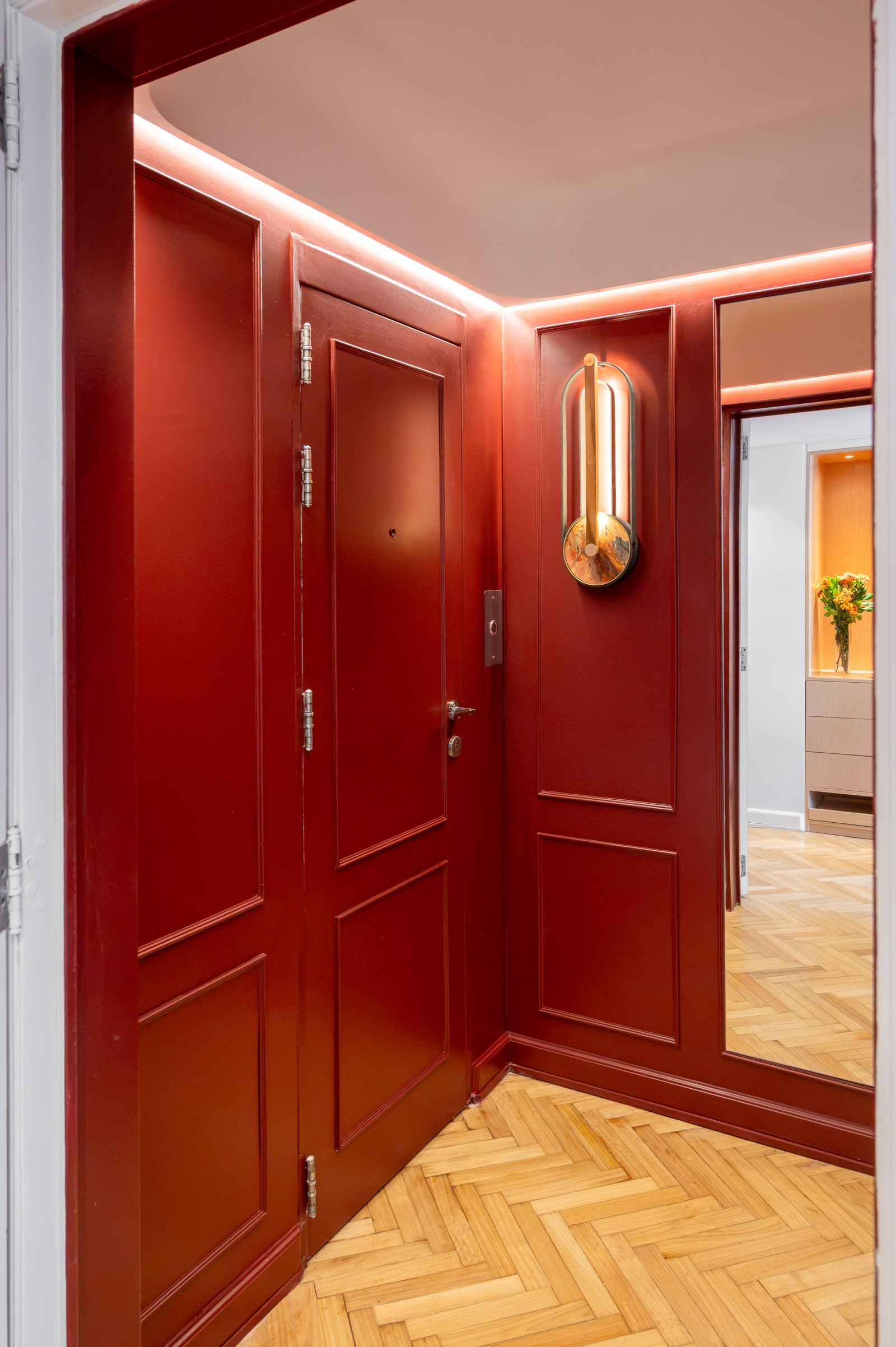 Pasillo rojo con puertas de madera, iluminación cálida y piso de espiga — proyecto ALVEAR TYM, por AB ARQUITECTURA, en Recoleta