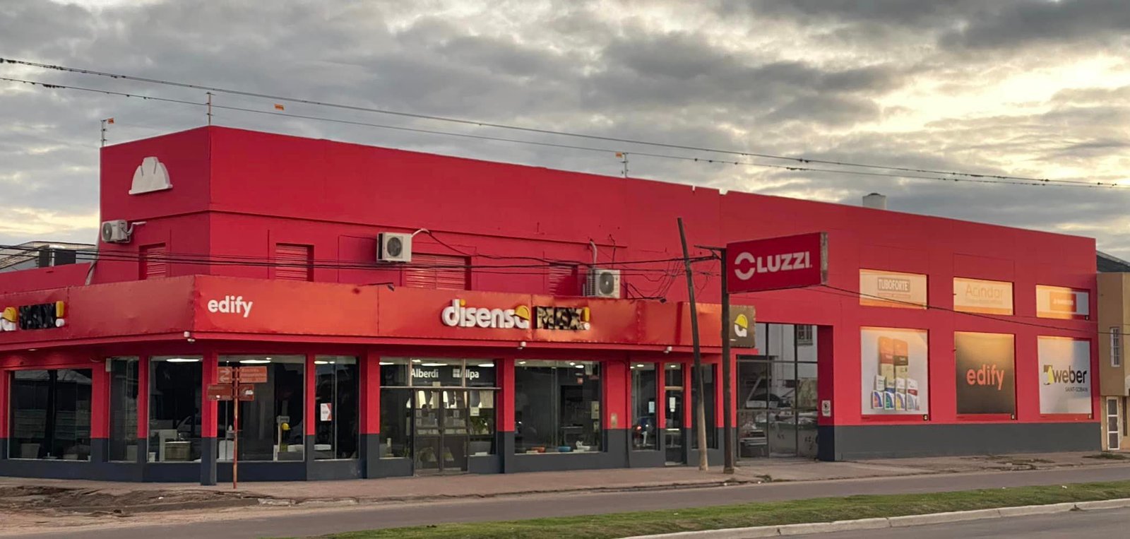 fachada comercial roja con toldo naranja y paneles de arte — proyecto Edify Casa central. Local de venta de materiales de Construccion., por Arquitecto Gustavo Maidana, en Corrient