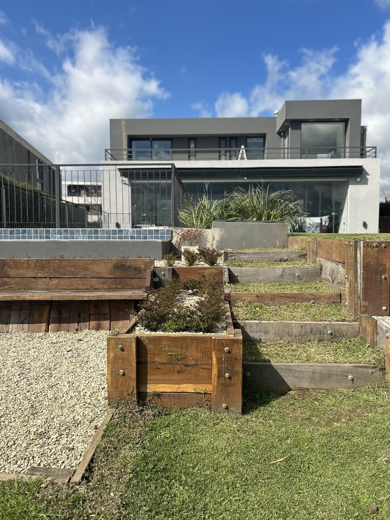 Fachada moderna con jardín en terrazas y piscina — proyecto Marinas House, por Fusión Nativa Estudio, en Puertos