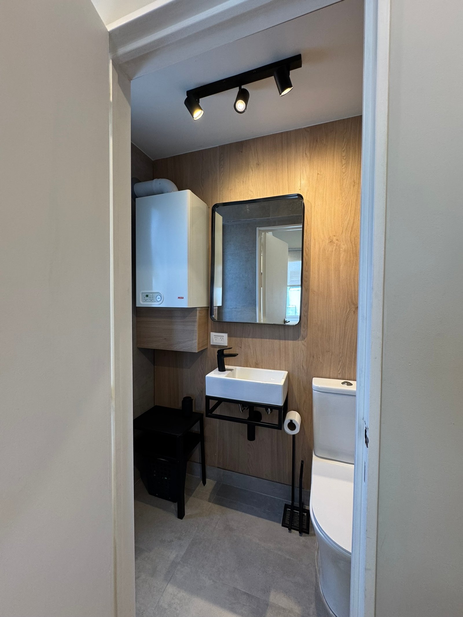 Baño moderno con paredes de madera y suelo de piedra — proyecto Matienzo, por MDBK Arquitectura, en Belgrano