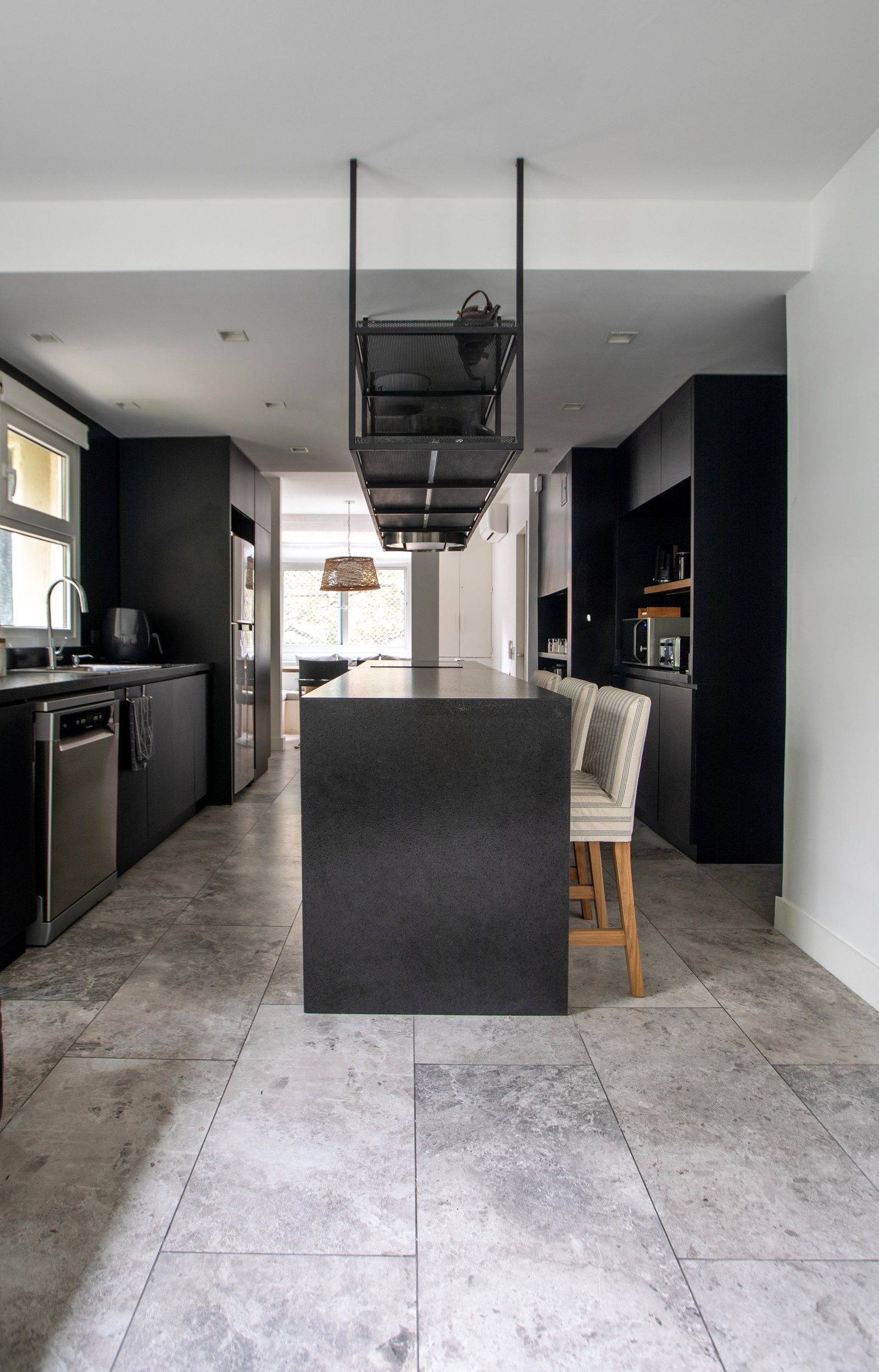 Cocina moderna con isla de piedra negra y suelo de mármol gris — proyecto PROYECTO PARQ, por ILVA, en Provincia de Buenos Aires