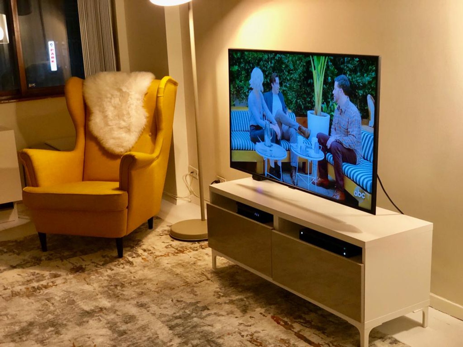 Sala de estar moderna com poltrona amarela e TV — projeto Depto NY, por DE DIOS Estudio, em Nueva York
