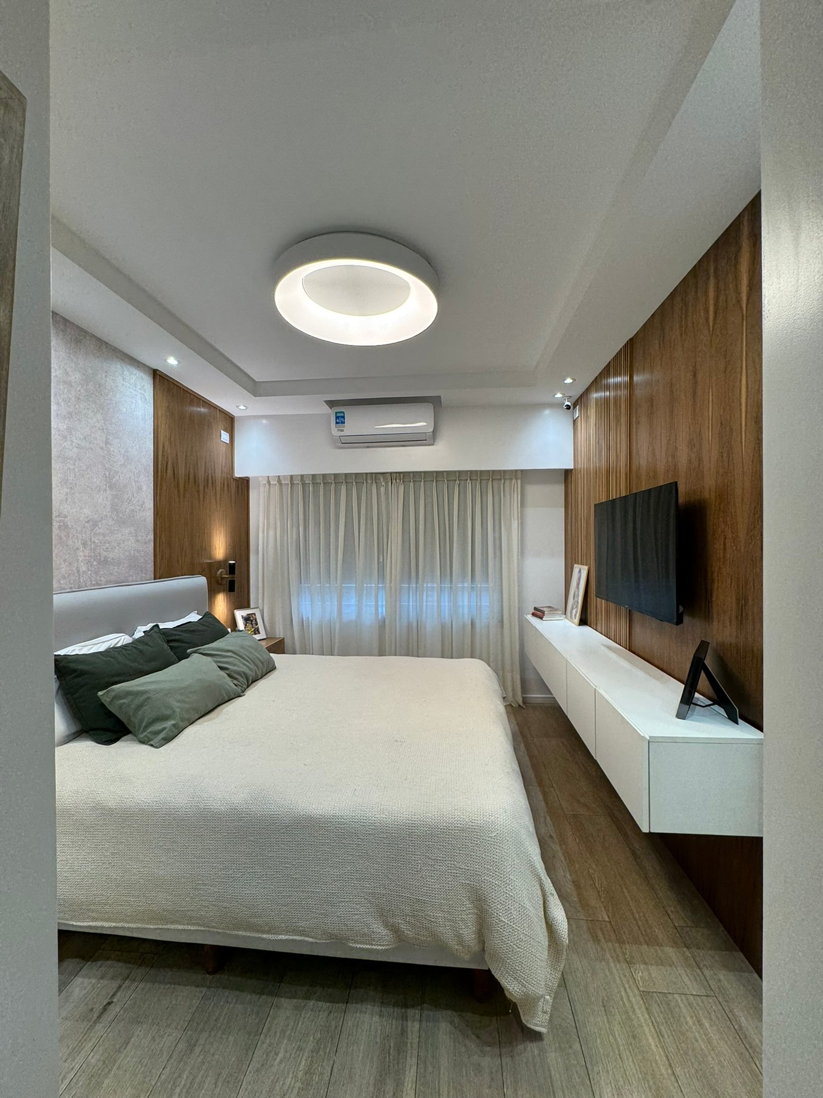 Quarto moderno com parede de madeira, TV e cama king — projeto Corrientes II, por MDBK Arquitectura, em Villa Crespo