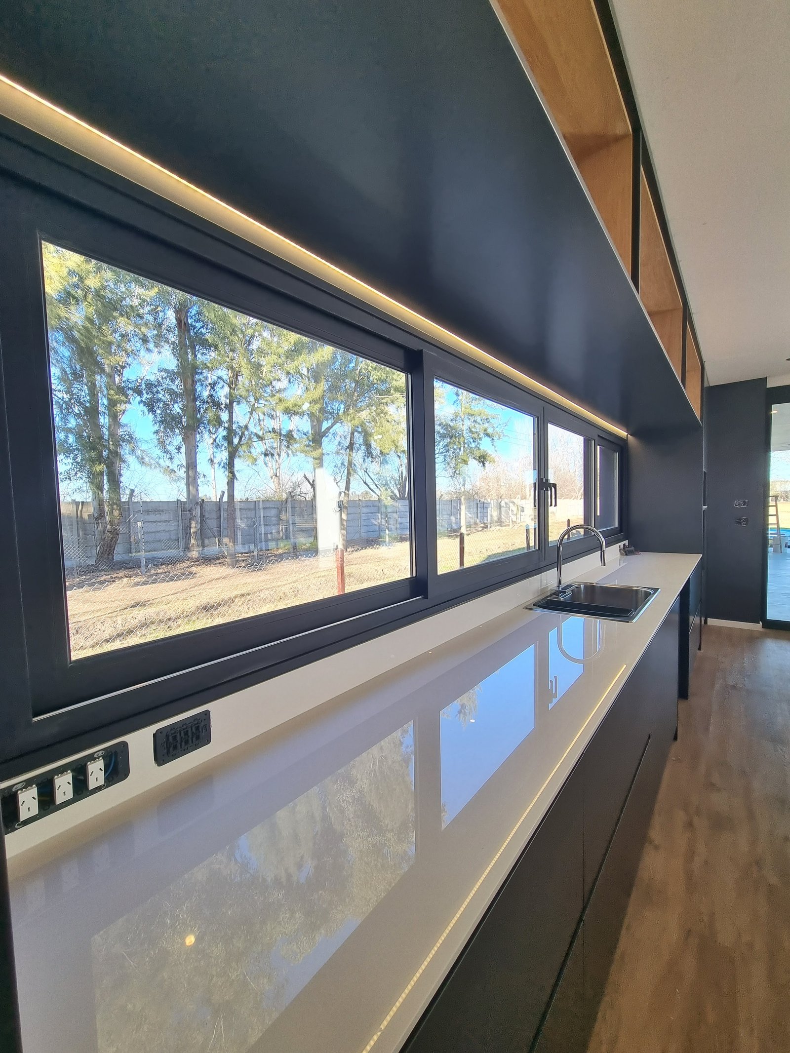Cozinha moderna com vista externa e bancada branca — projeto CASA T199, por A'PRIMA - Arquitectura Sustentable, em Los Robles 5901