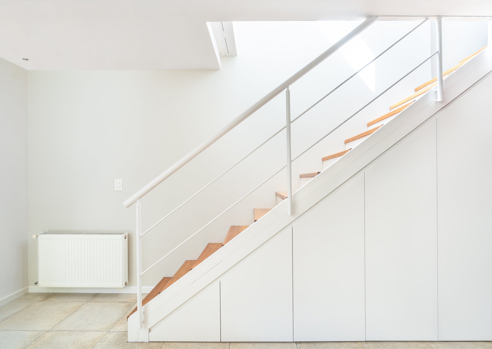 Escalera moderna blanca con almacenamiento integrado y baranda minimalista — proyecto SANTA FE, por Maria Menna Arquitecta, en Mar del Plata