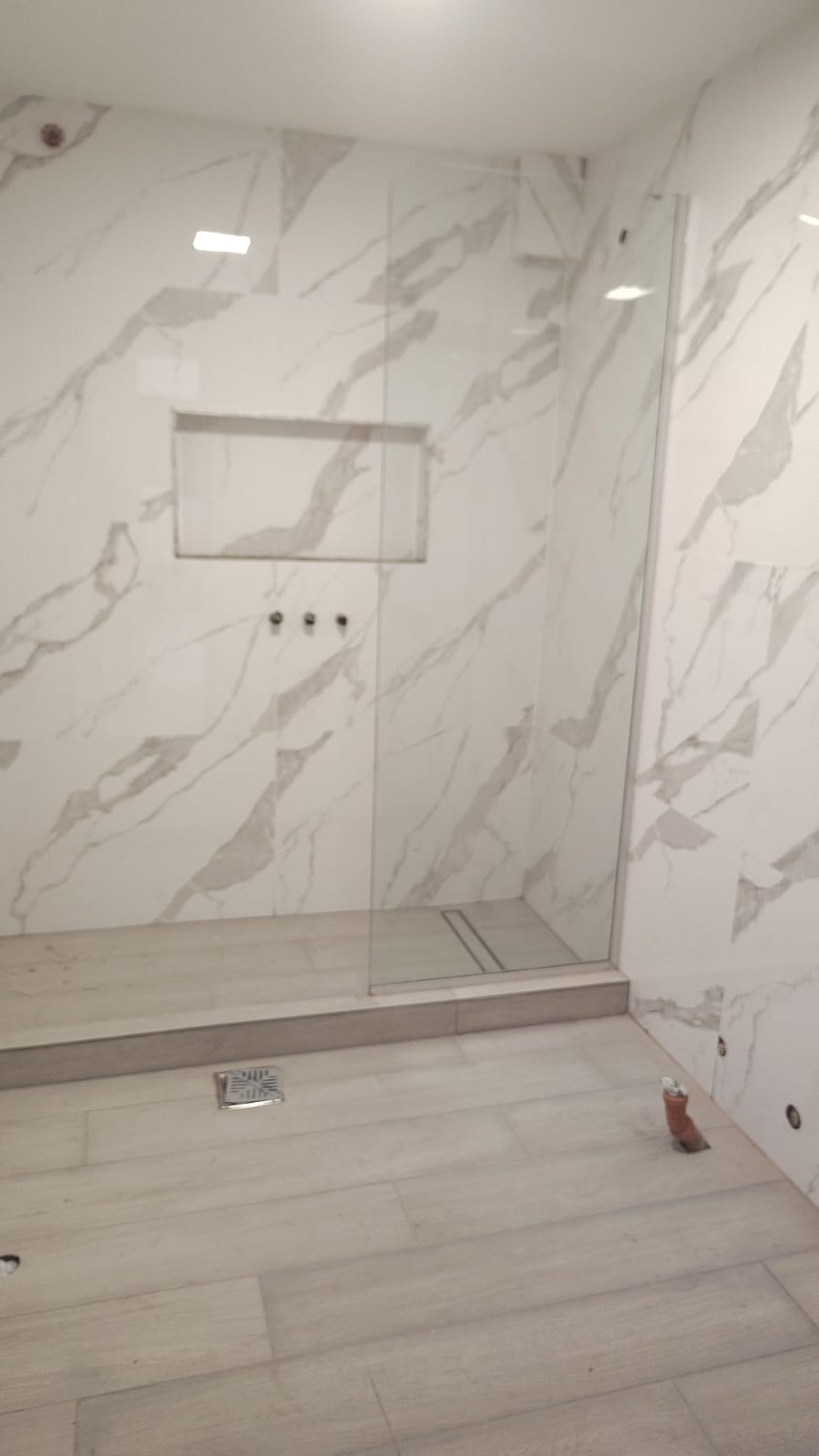 Baño moderno en construcción con revestimientos de mármol y cerámica — proyecto Remodelación de baño, por CN Construcciones, en Alta Gracia