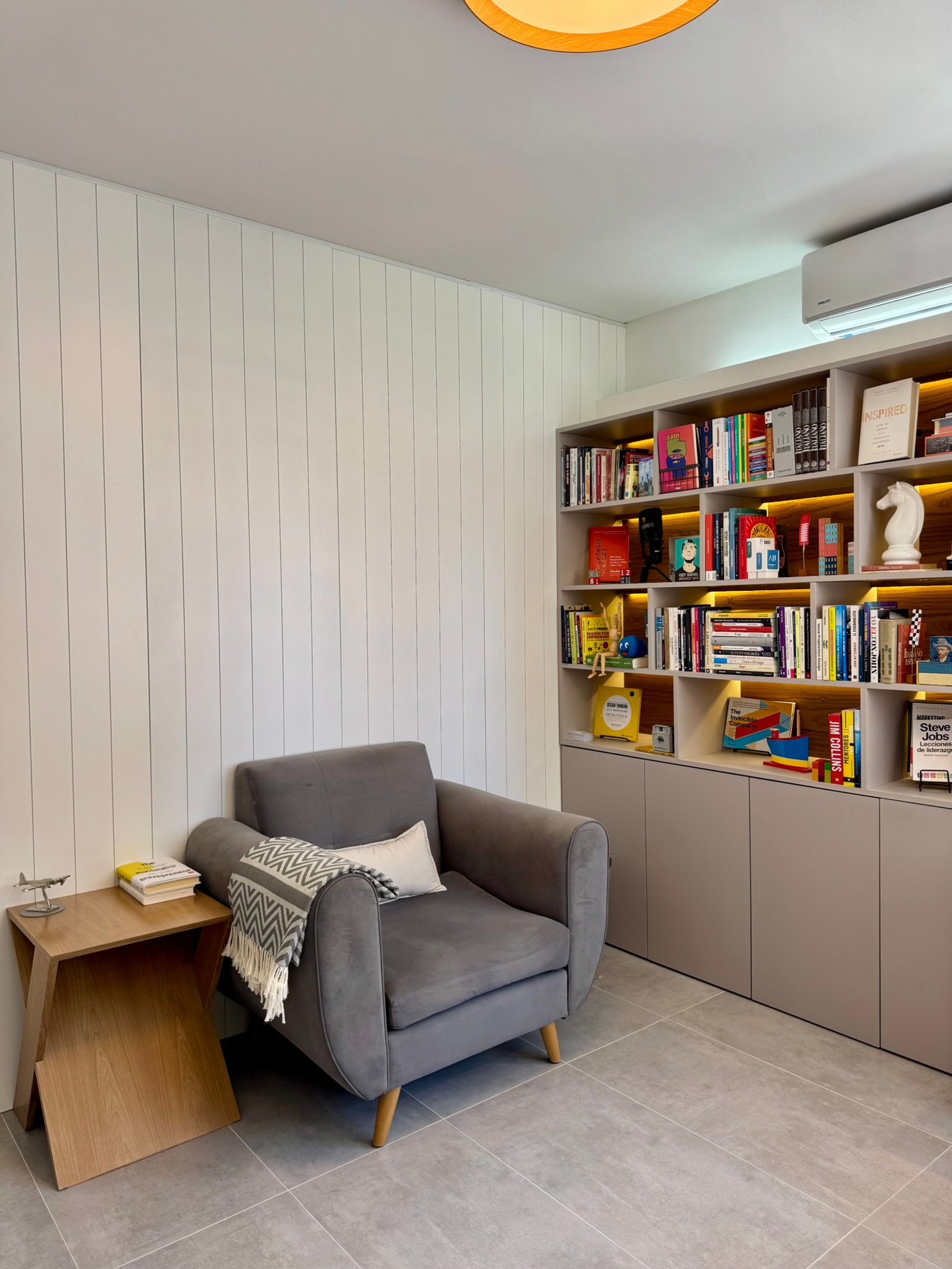 Sala de estar moderna com poltrona cinza e prateleiras embutidas — projeto Matienzo, por MDBK Arquitectura, em Belgrano