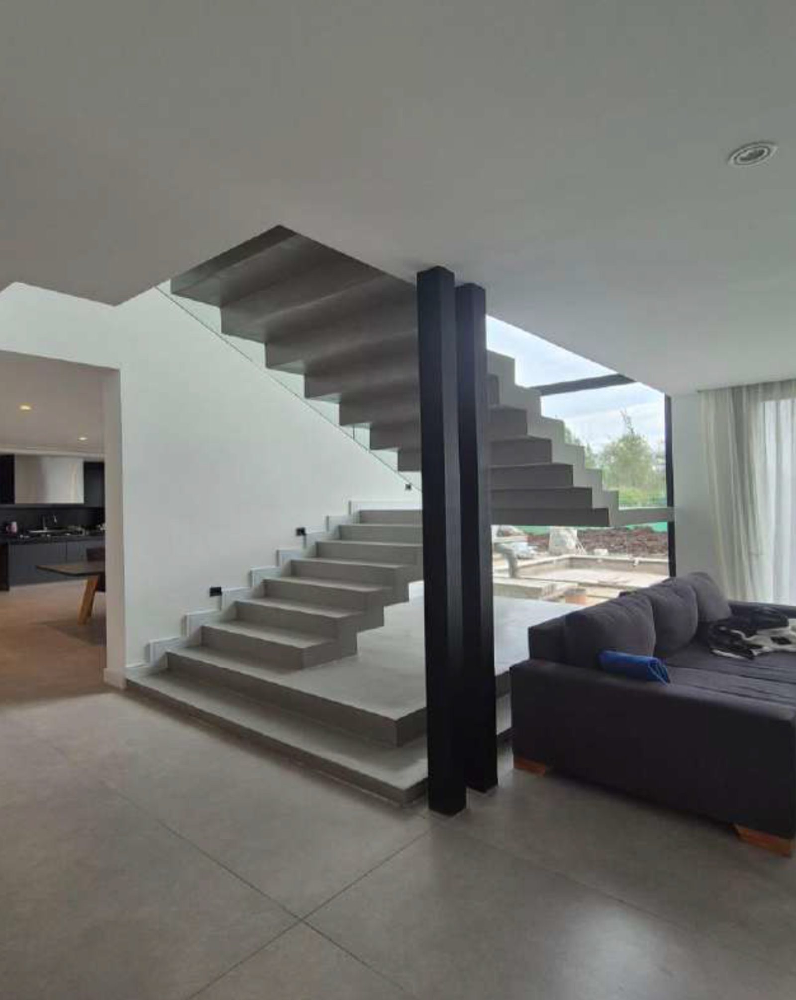 Escada flutuante moderna com sala e sofá cinza — projeto Vivienda Laggon, por MMCZ STUDIO, em R. Caamaño 1106
