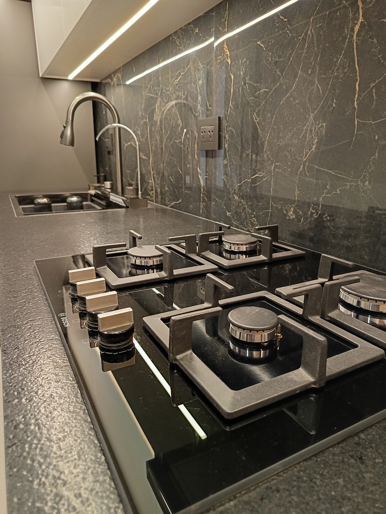 Cocina moderna con pared de mármol negro e iluminación indirecta — proyecto Obra pelle, por vetainteriores, en Av. Carlos Pellegrini 1400