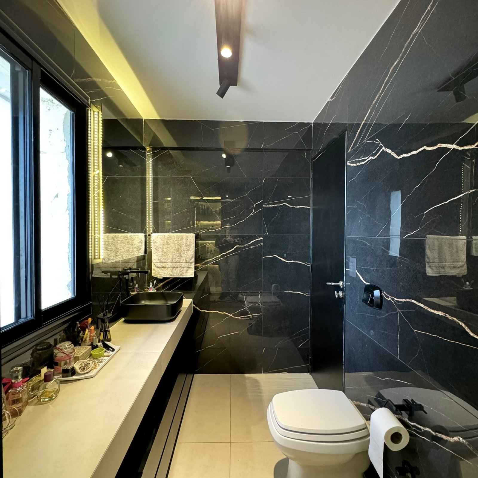Baño moderno de mármol negro con detalles minimalistas y luz indirecta — proyecto Coronel Diaz, por MDBK Arquitectura, en Palermo