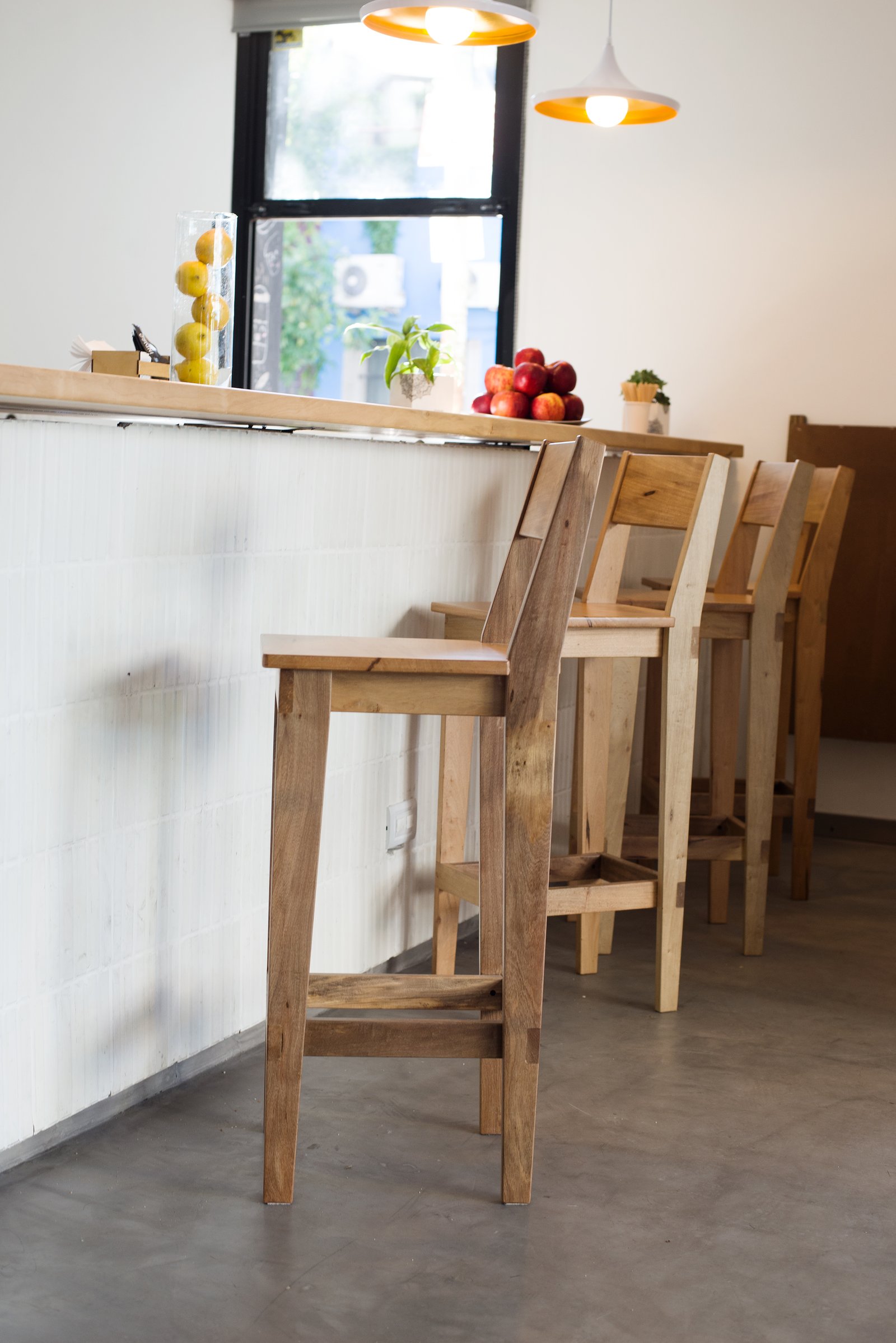 Bancos de madera rústicos en barra con luces naranjas — proyecto CHEILE - Cafe&Restó, por GALPON OSUNA, en Buenos Aires