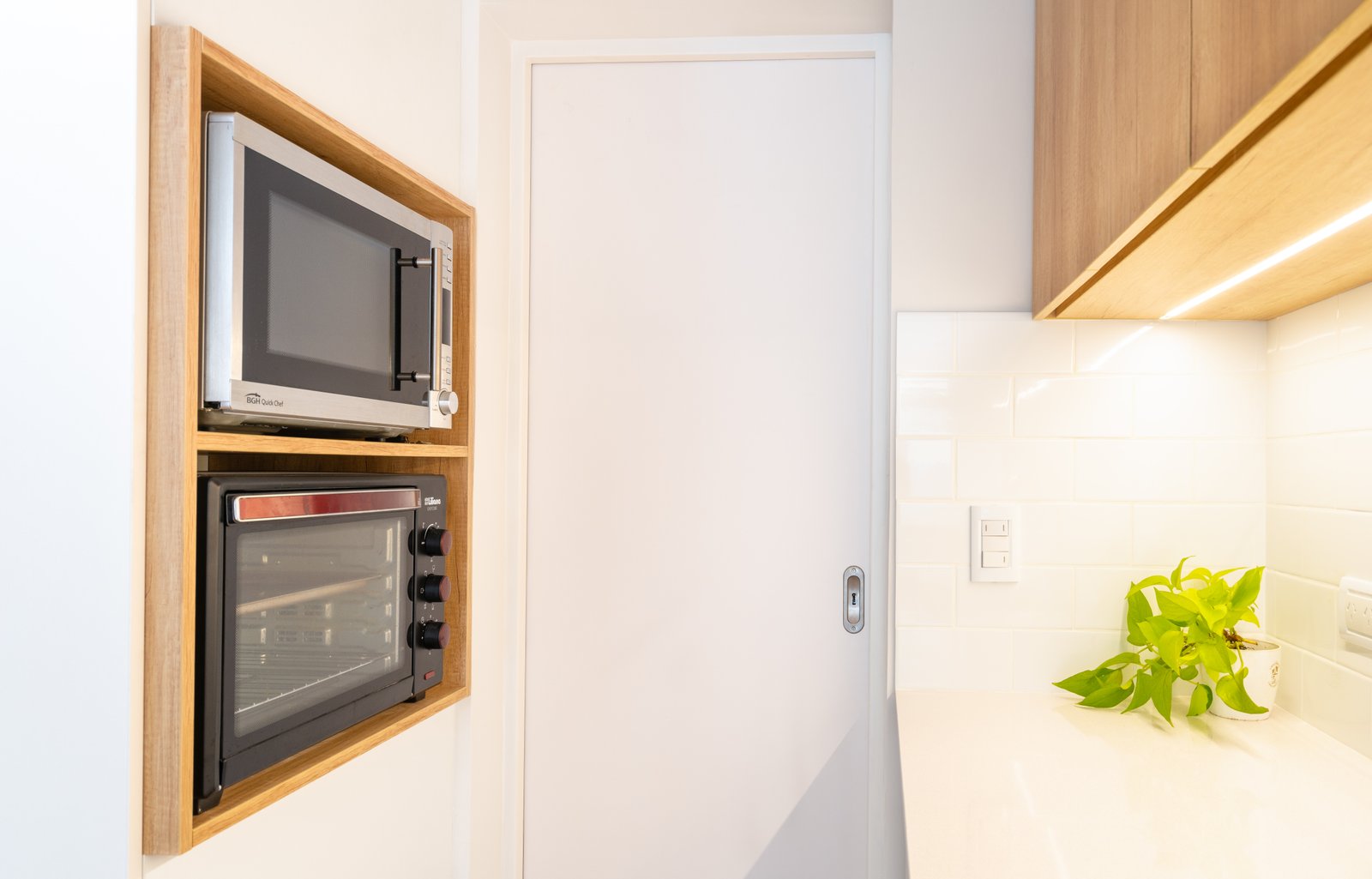 Cocina moderna con hornos empotrados y estanterías de madera — proyecto SANTA FE, por Maria Menna Arquitecta, en Mar del Plata