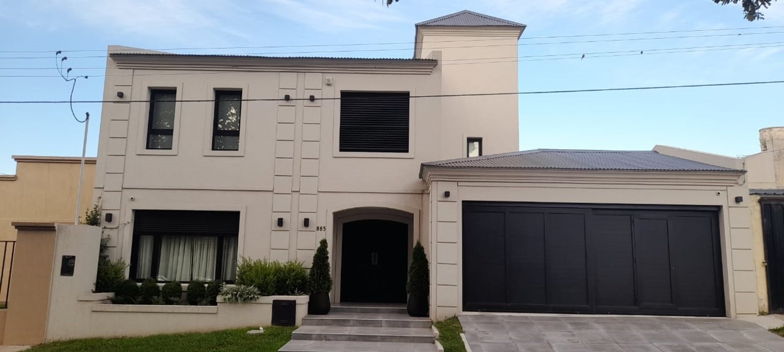 Fachada de casa moderna com detalhes clássicos e garagem preta — projeto Casa FF, por Forma, em Balcarce