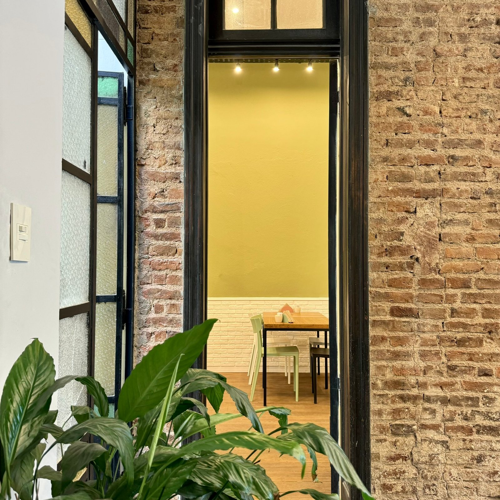 Sala de jantar industrial com paredes de tijolo exposto e mesas de madeira — projeto UGA Coffee House, por MDBK Arquitectura, em Almagro