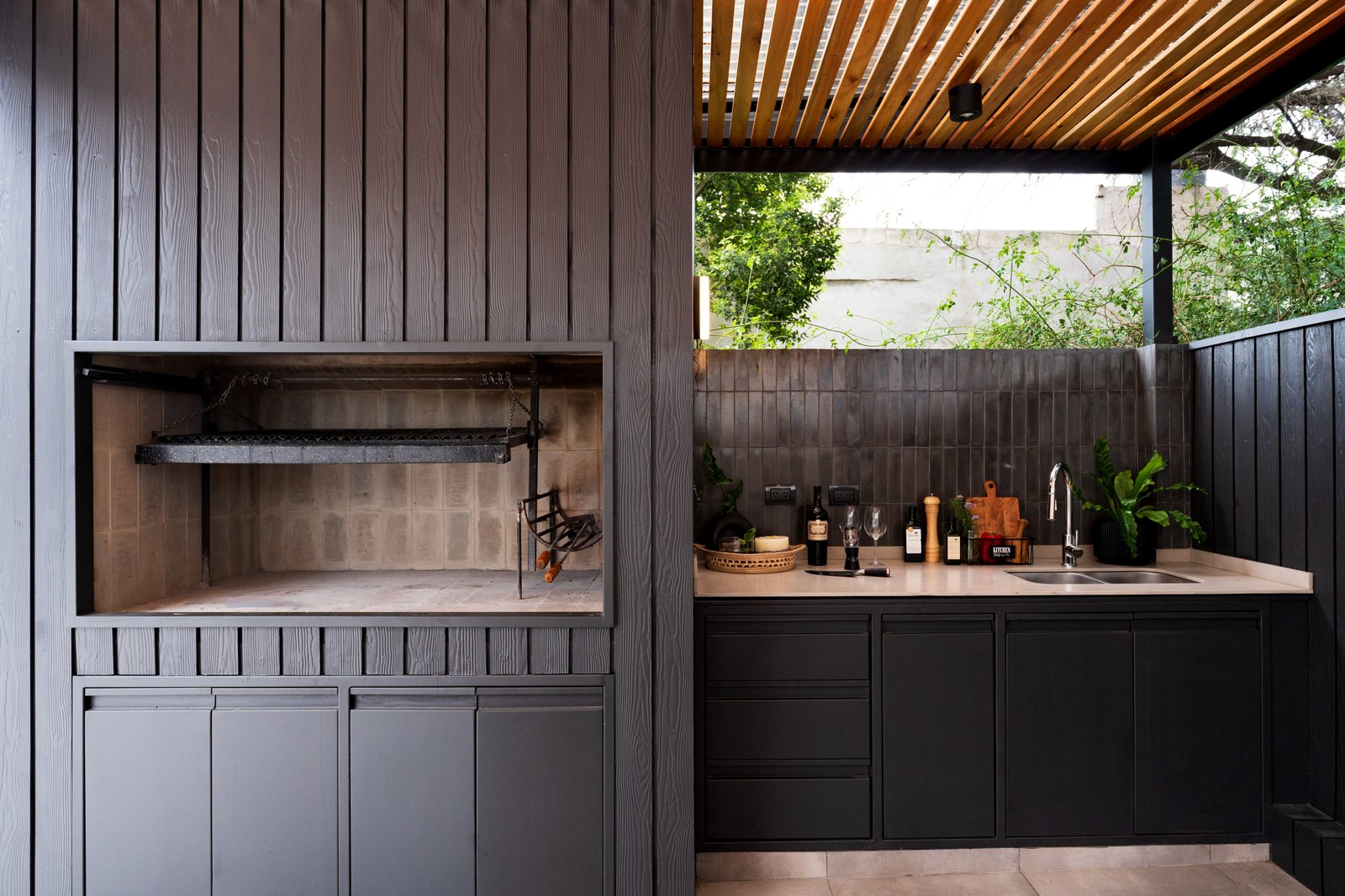 área de quincho moderna con revestimiento de madera y parrilla integrada — proyecto TERRAZA MARCOS SASTRE, por FARQ ESTUDIO, en Villa del Parque
