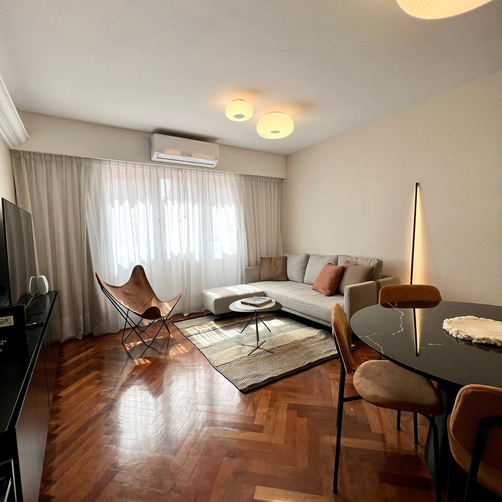 Living moderno con sillón beige y butaca butterfly — proyecto Perón , por MDBK Arquitectura, en Barrio Norte