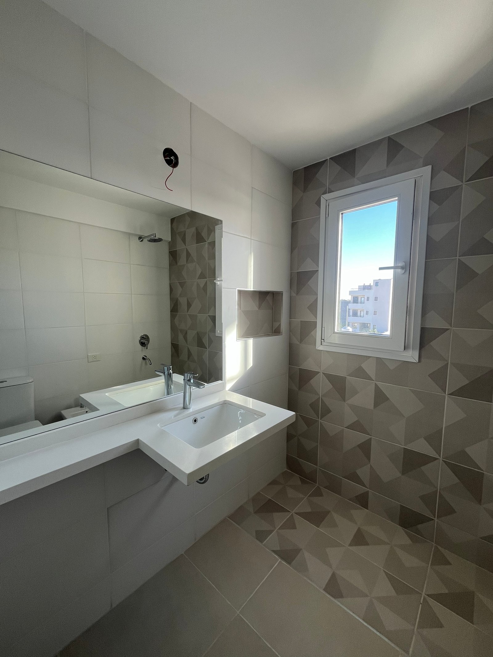 Baño moderno con azulejos geométricos y tocador minimalista — proyecto Edificio Tucumán 240, por Maria Elena Brusa, en Viedma