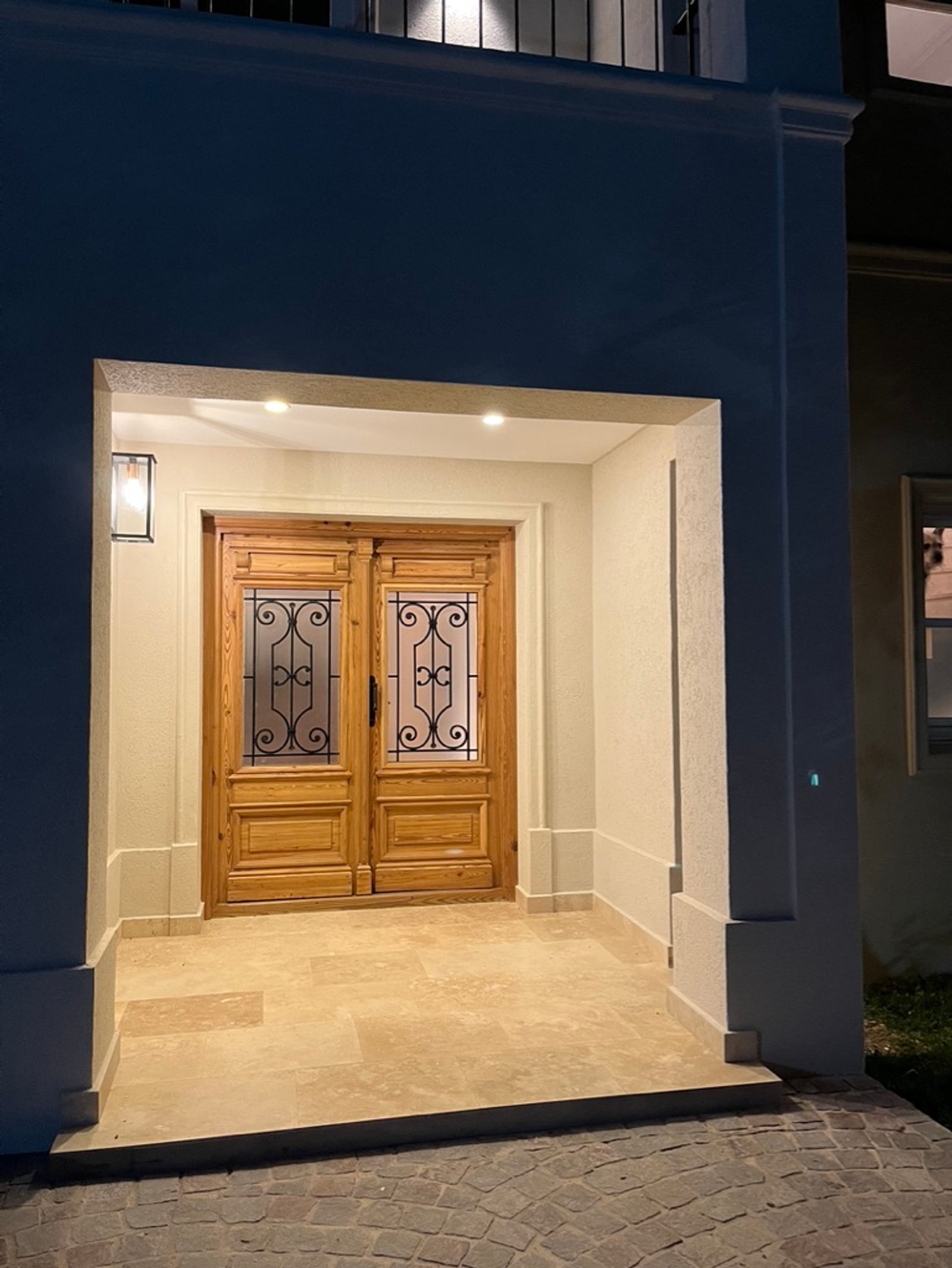 entrada principal de madera con detalles de hierro forjado y luces cálidas — proyecto Reforma integral Vivienda., por Arcucci Arquitectura, en Campo Grande