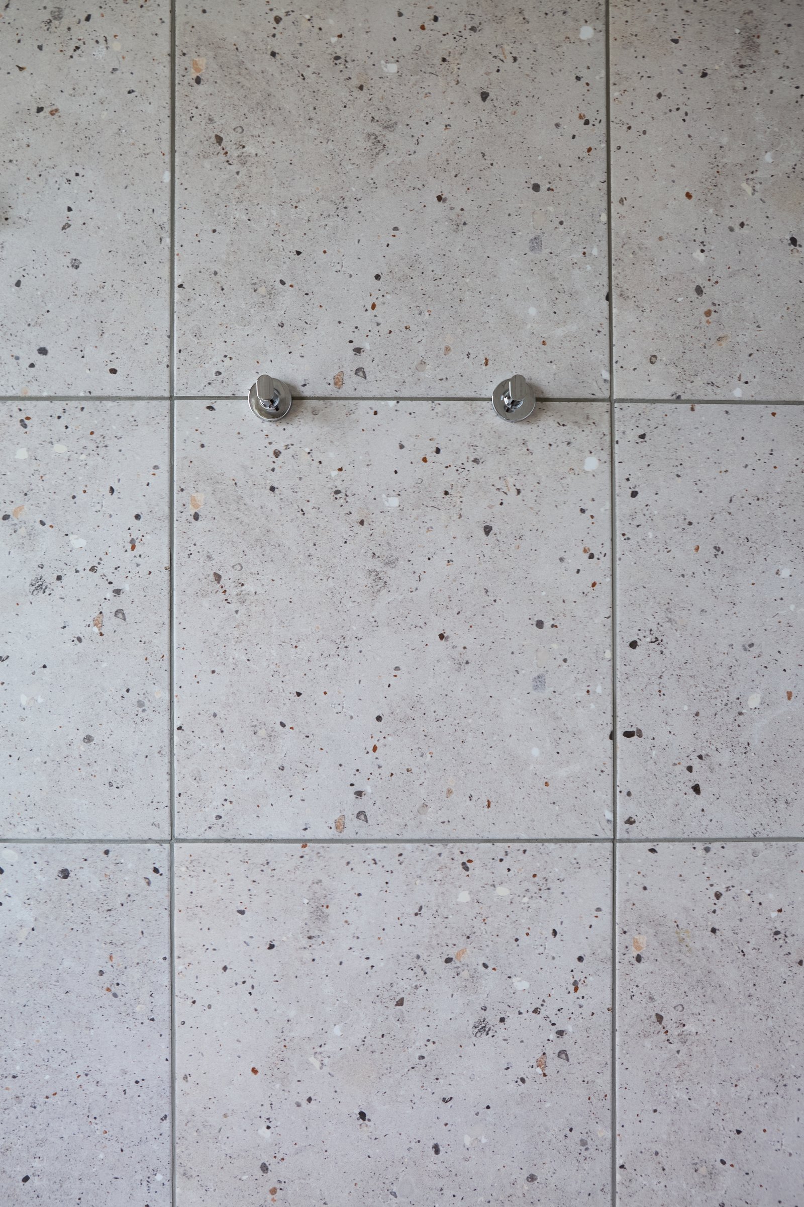 Baño moderno con paredes de terrazo y ganchos metálicos minimalistas — proyecto Baños, por CASA1-TROMEN, en Bella Vista