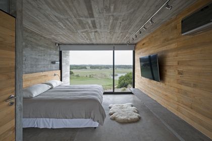 Dormitorio moderno con cama frente a ventanal panorámico de campo — proyecto Casa Golf, por Luciano Kruk